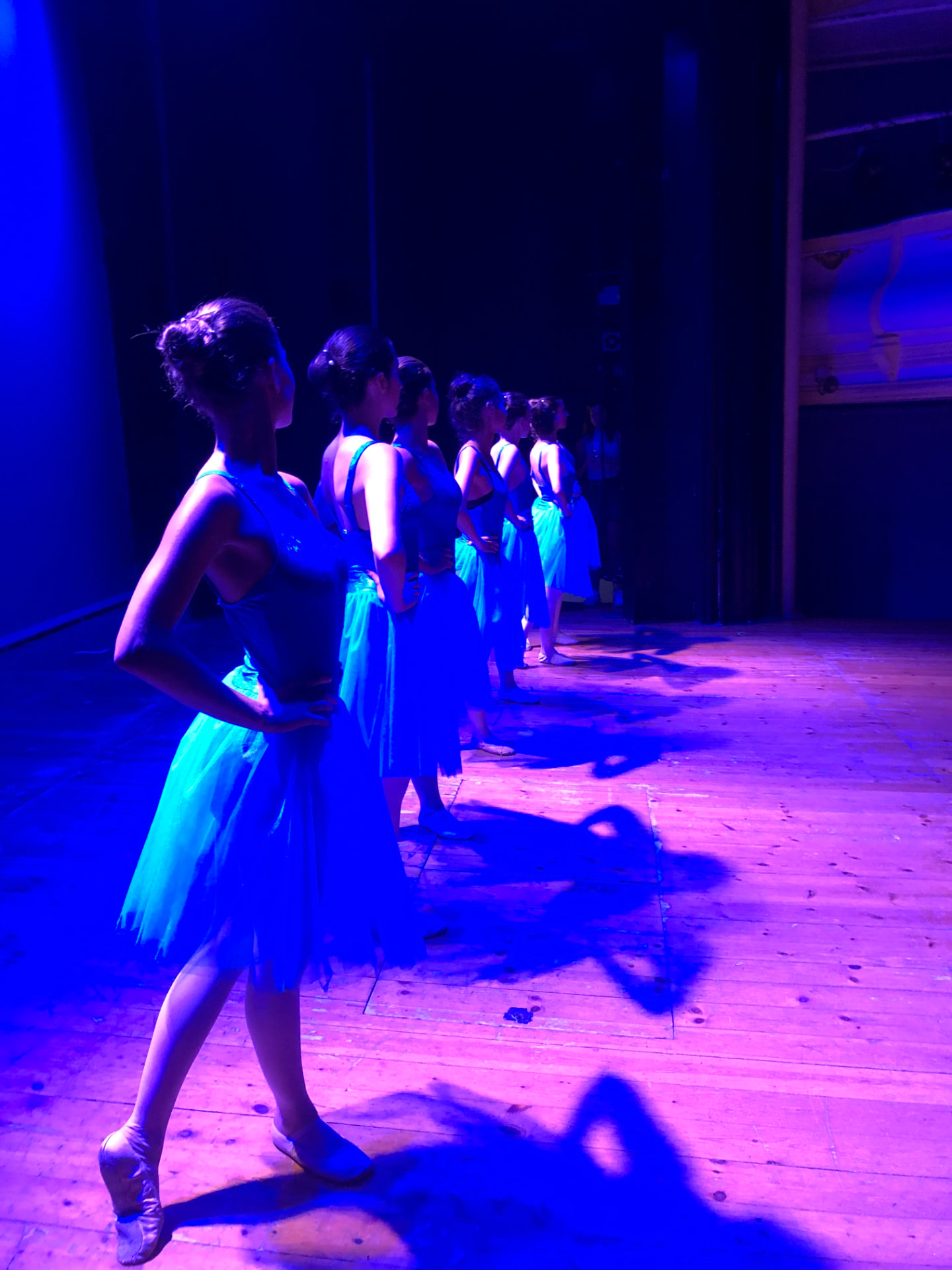 Classe de ballet clàssic a la barra amb la professora corregint la postura